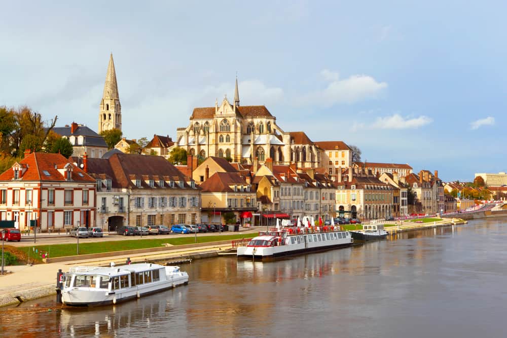 The beuatiful city of Auxerre in Burgundy, France. River with boats and in the background old buildings and church towers.
