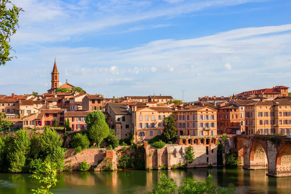 The beautiful houses of Albi in France. A river and bridge visible in the foreground.