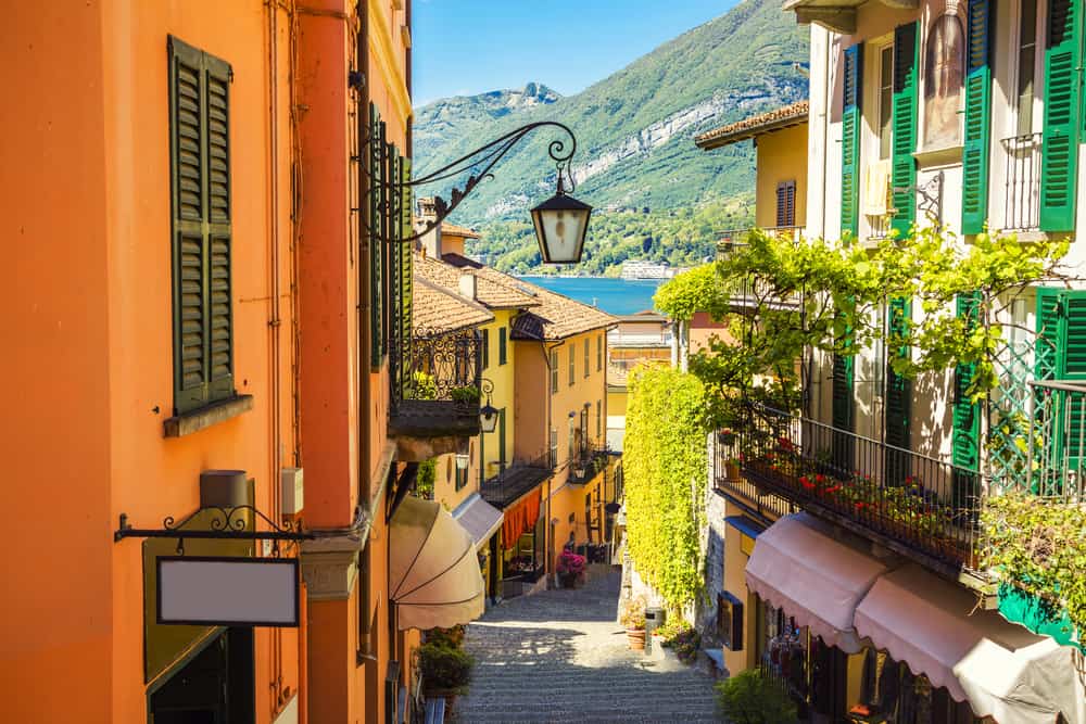Small street in Bellagio with colorful buildings and Lake Como in the horizon.