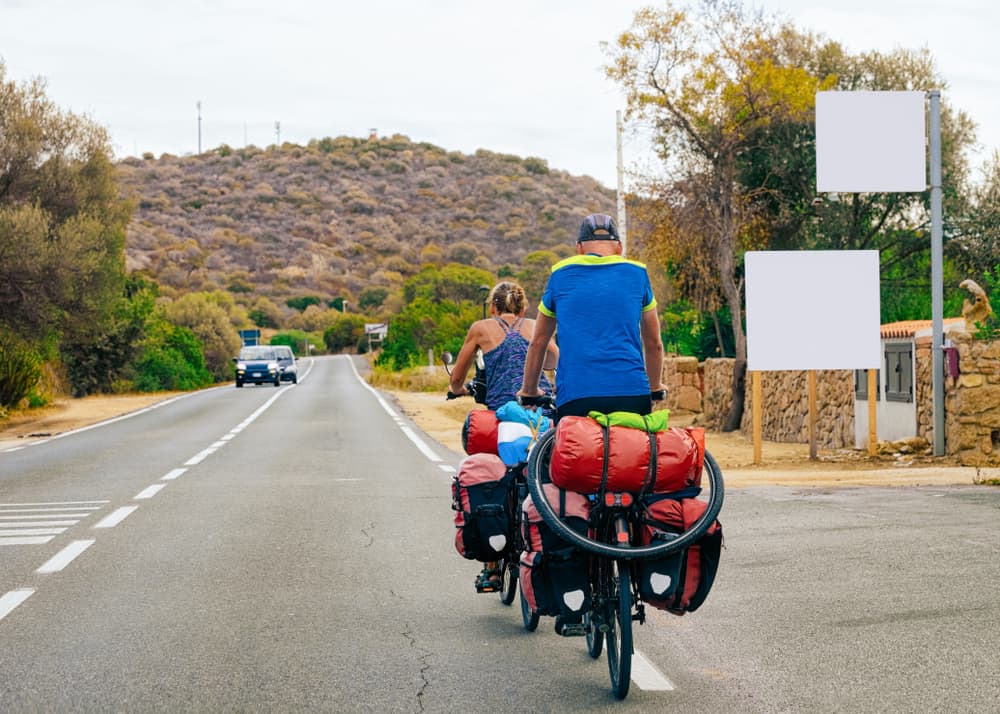 Two adult with a lot of gear bicycling on a road in Sardinia, Italy.