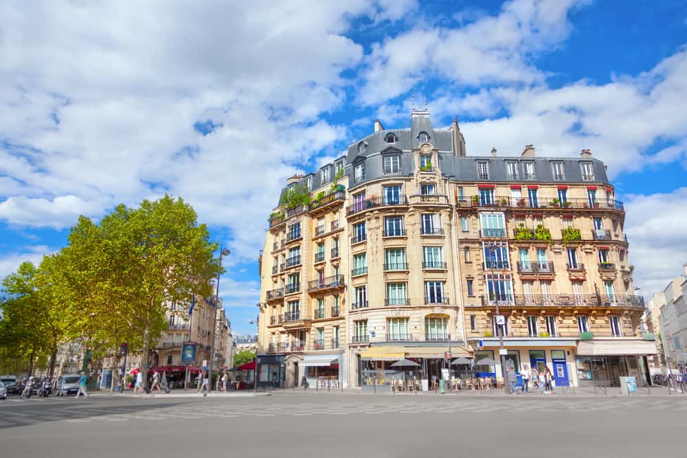 Boulevard du Montparnasse. A typical Parisian street with a huge building in the back, trees, and blue sky.
