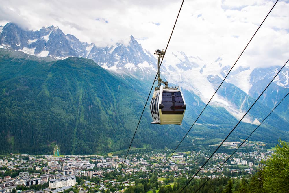 A cable car traveling over Chamonix, France. The city below and the Mont Blanc mountains in the back.