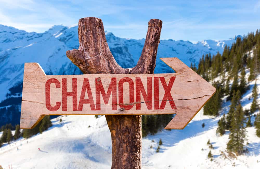 Wooden sign with the text "Chamonix". Snowy mountains in the background.