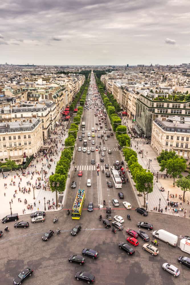 Skyline view of Champs-Élysées in Paris with street filled with cars and pedestrians.