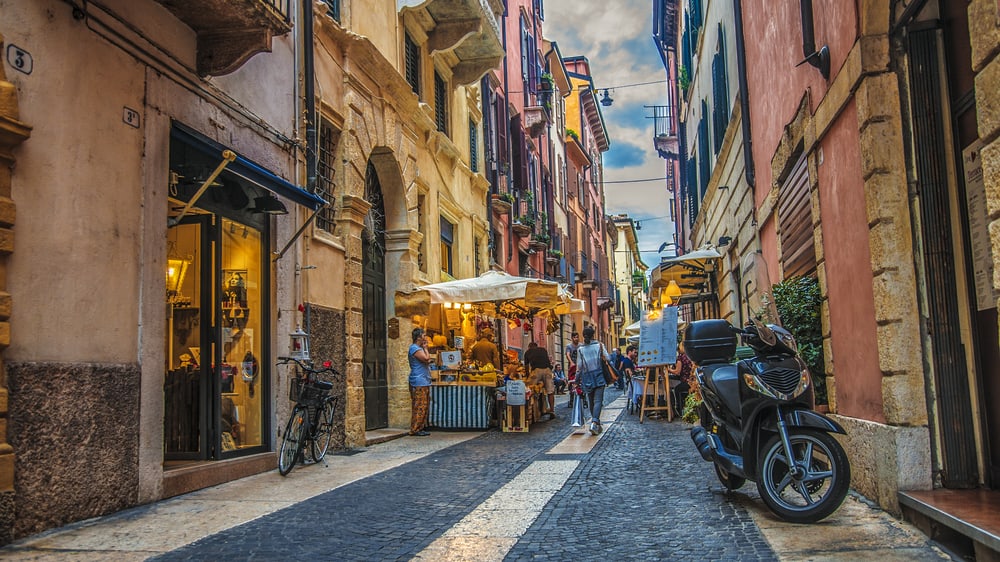 A narrow and cozy street in Verona with small shops, old houses, and pedestrian.