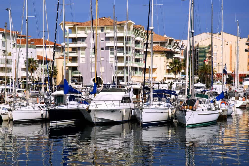 The small port of Fréjus in France. Small boats in calm water and houses in the background.