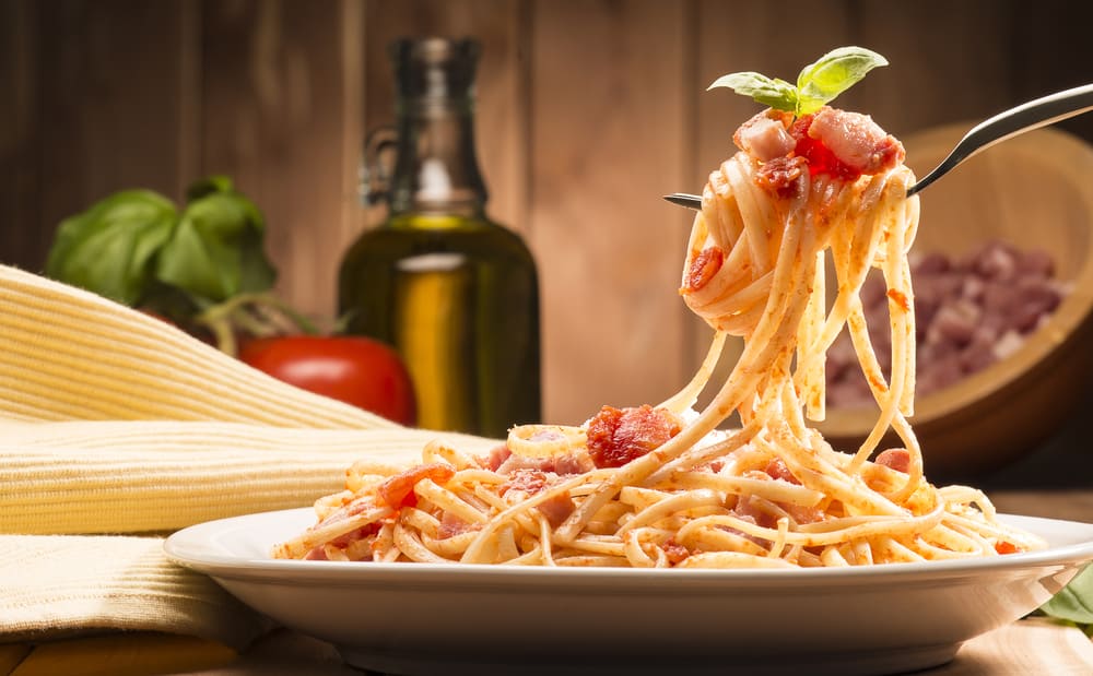 Typical Italian spaghetti meal served on a plate. A fork is holding some of the pasta.