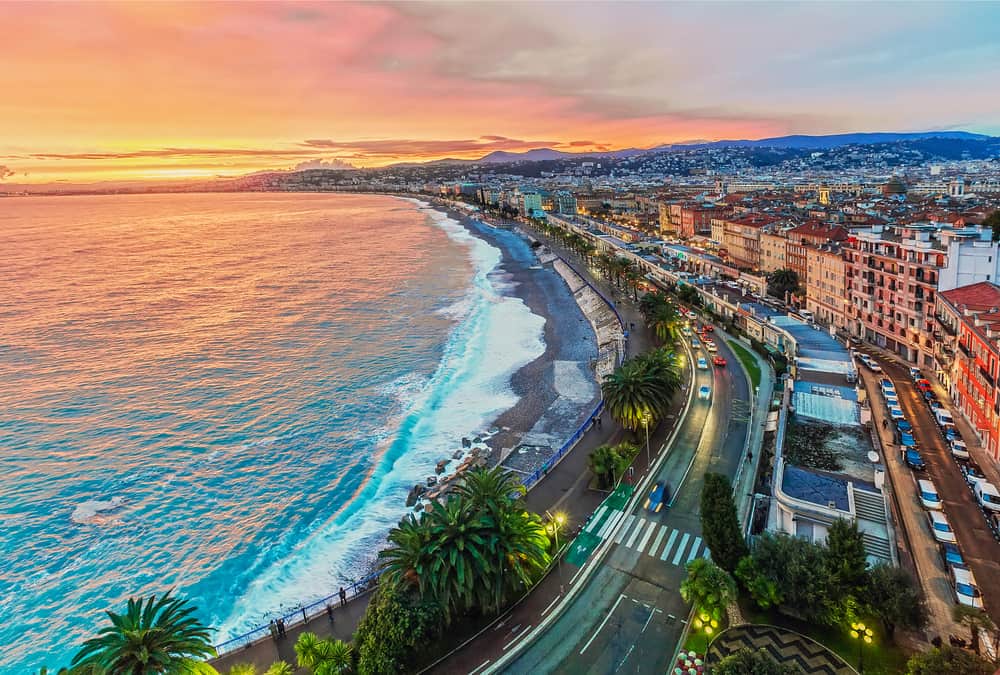 Aerial view of Nice at dusk. Ocean, beach, and road along the city.