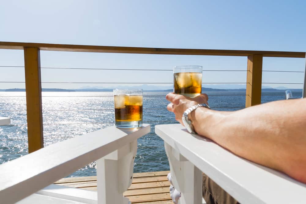Passenger sitting on a cruise ship enjoying the view and having a drink.