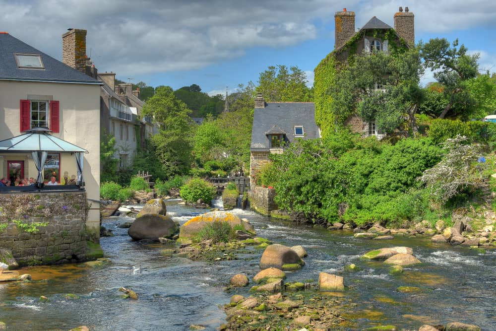 A few houses in the town of Pont-Aven in France. A stream running next to the buildings.