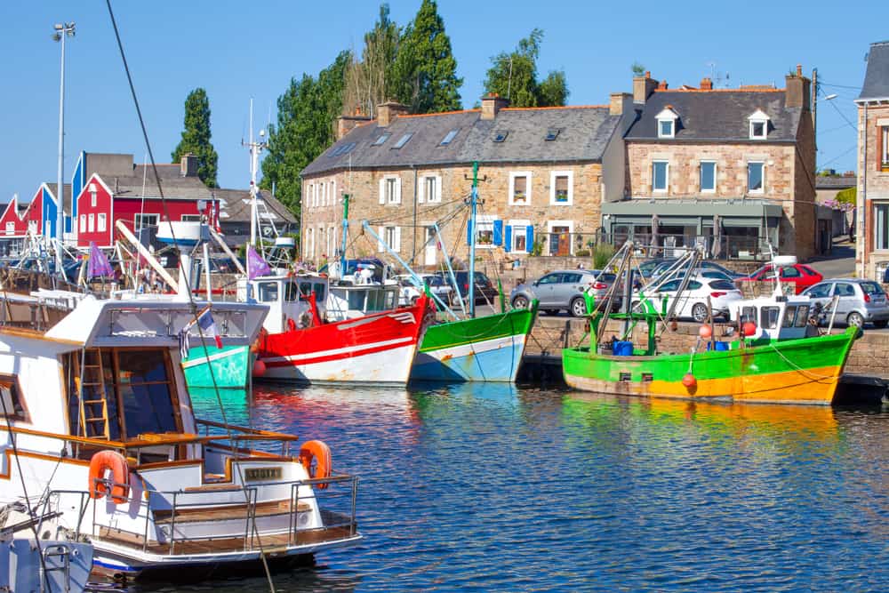 The cozy port of Paimpol in Brittany, France. Small fishing boats in the water and houses in the background.