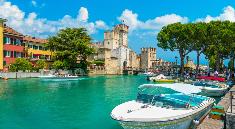 The beautiful town of Sirmione by Lake Garda, Italy. Boats in the front and the town castle in the background.