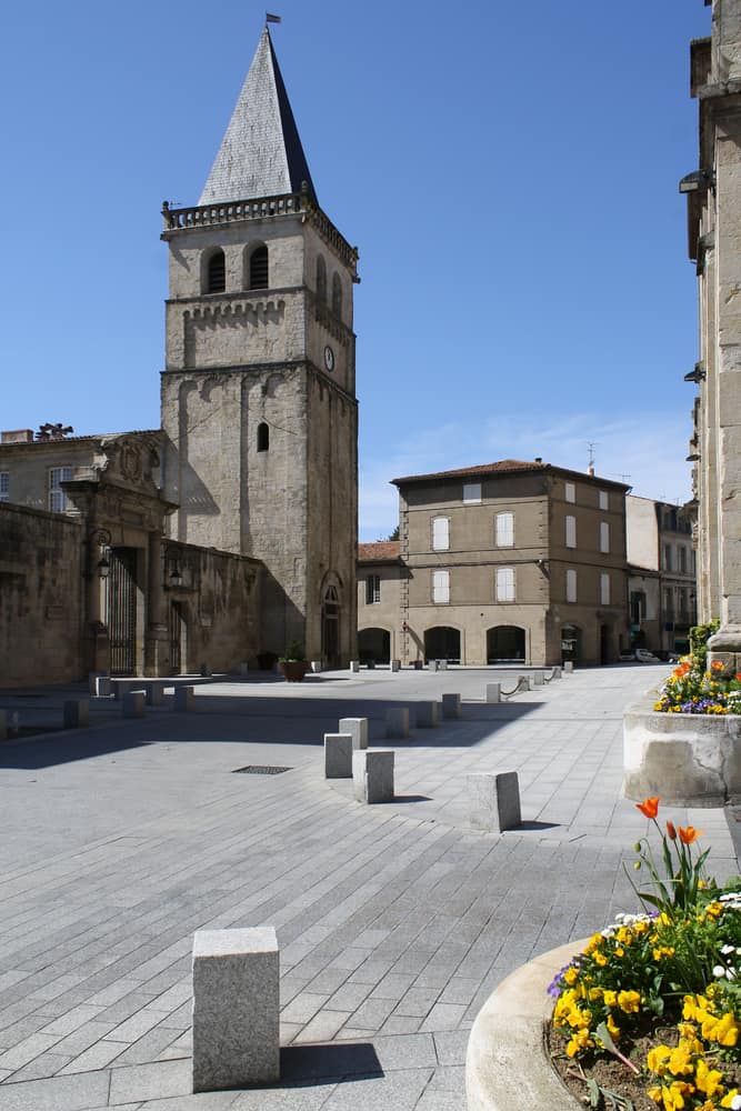 A square in Castres, France with a big clock tower and old buildings.