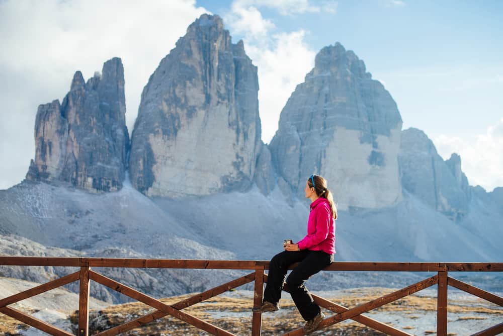 Yong woman with a cup of coffee enjoying the view of the Dolomites in Italy.