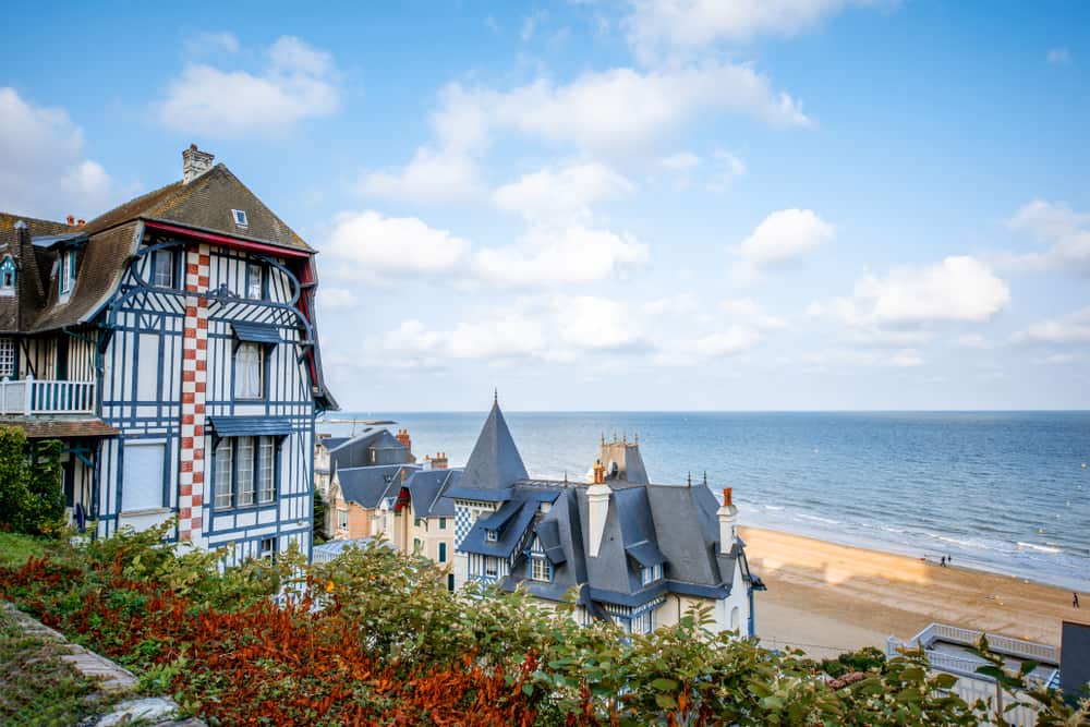 Nice houses in Trouville, France overlooking the beach and the ocean on a clear blue day.