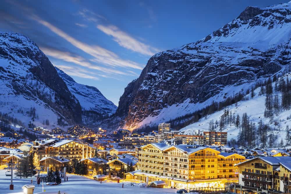 The ski resort town of Val d'Isere in the French Alps. Nighttime with the buildings lighting up and the mountains in the background.