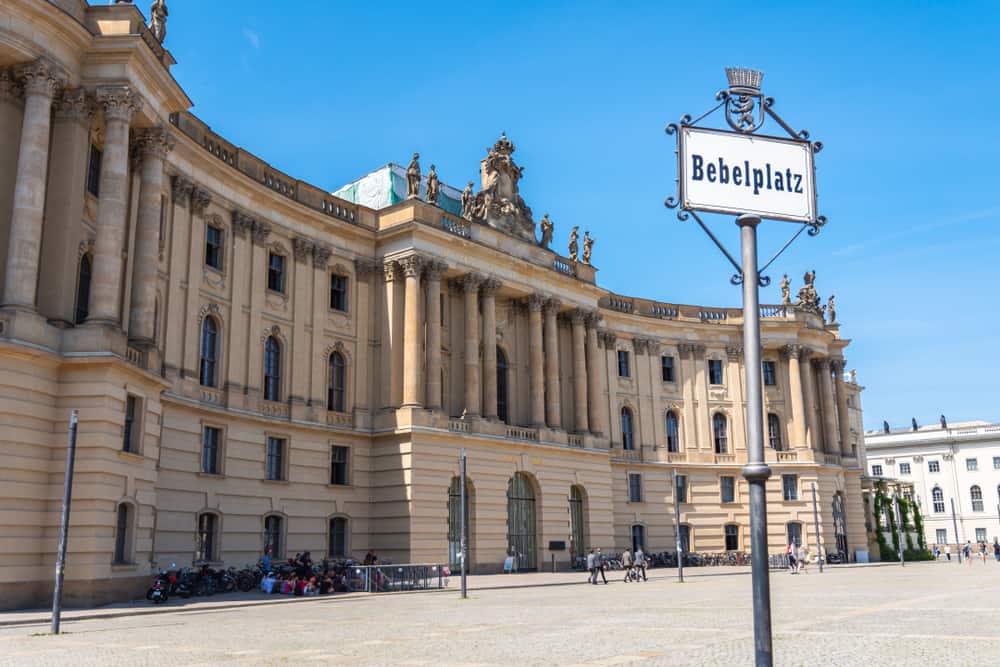 Location sign of Bebelplatz in the Mitte district of Berlin, Germany. In the back an old and majestic building.