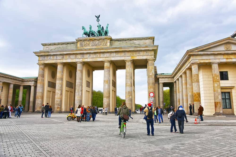 The famous landmark of Berlin; The Brandenburg Gate. Pedestrians on the Pariser Platz on a bright day.