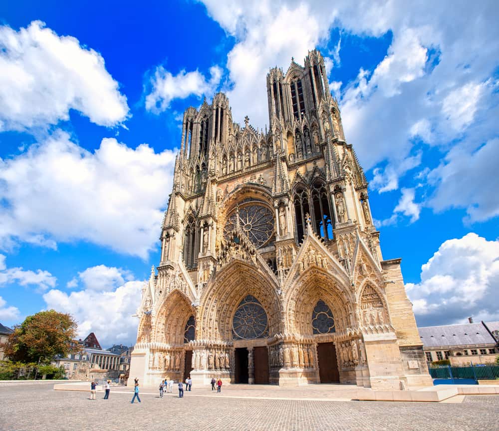 Outside view of the majestic Cathedral Notre-Dame in Reims, France. Blue sky and a few tourists.