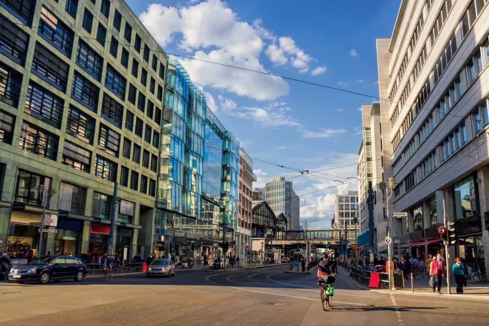 A view down Friedrichstraße in Berlin Mitte. Tall buildings, cars, bicycles, and pedestrians.