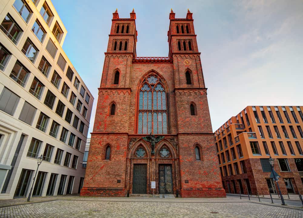 Outside view of the Friedrichswerdersche Kirche in Berlin, Germany. The front of the church with its two towers is squeezed in between two other large buildings.