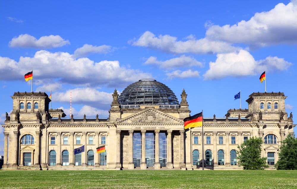 Outside view of the Reichstag building in Berlin, Germany. German flags and blue sky.