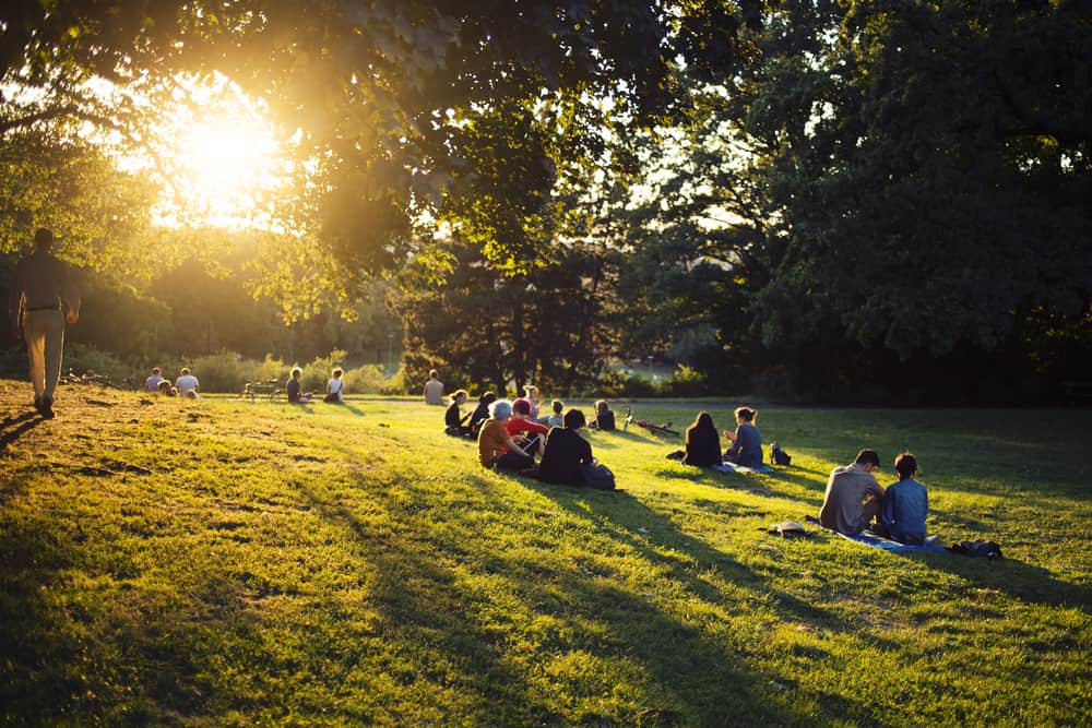 Viktoriapark in the Kreuzberg district of Berlin, Germany. Young people sitting on a lawn in the sunset.