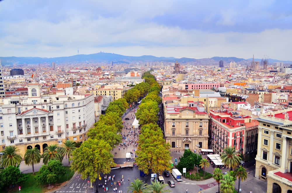 Aerial view of the busy street Las Ramblas in Barcelona, Spain. Mountains in the background.