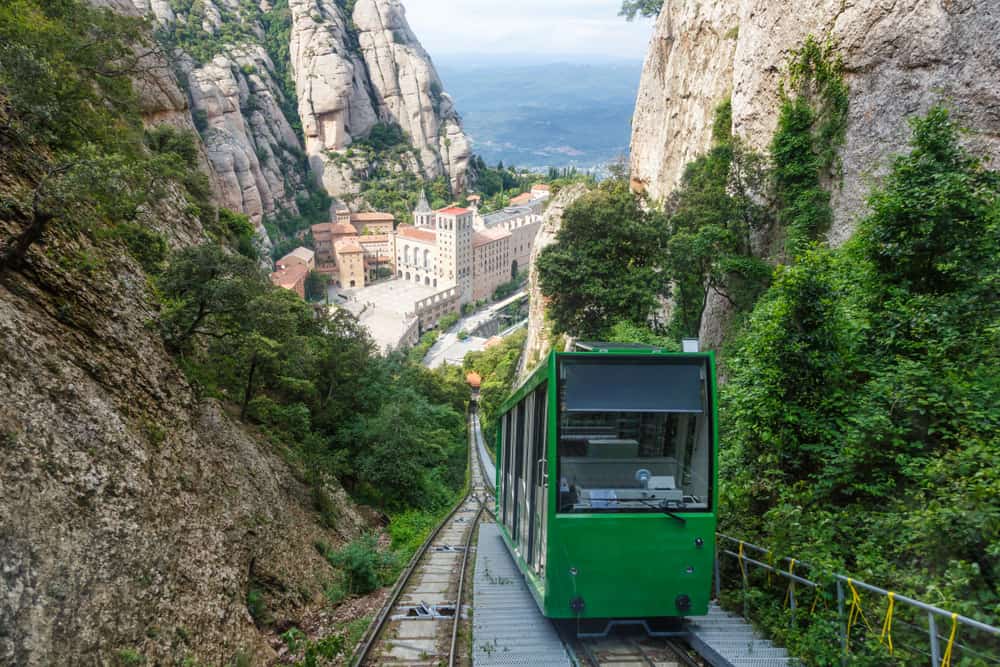 Green funicular going up a mountain transporting tourist to Montserrat near Barcelona in Spain.