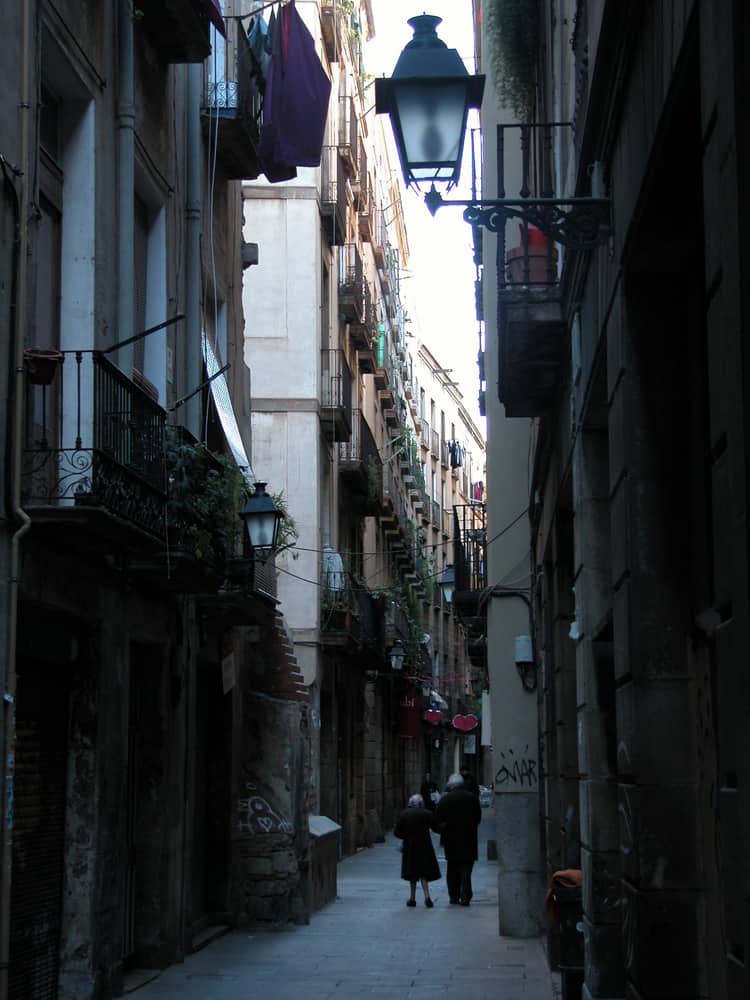 Narrow steet in the El Born district in Barcleona Spain. Elderly couple walking hand in hand.